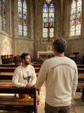 Two Fraternity brothers in a Catholic church with stained glass windows and wooden pews.